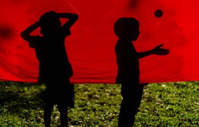 The silhouette of two boys playing behind a red cloth in Bangladesh