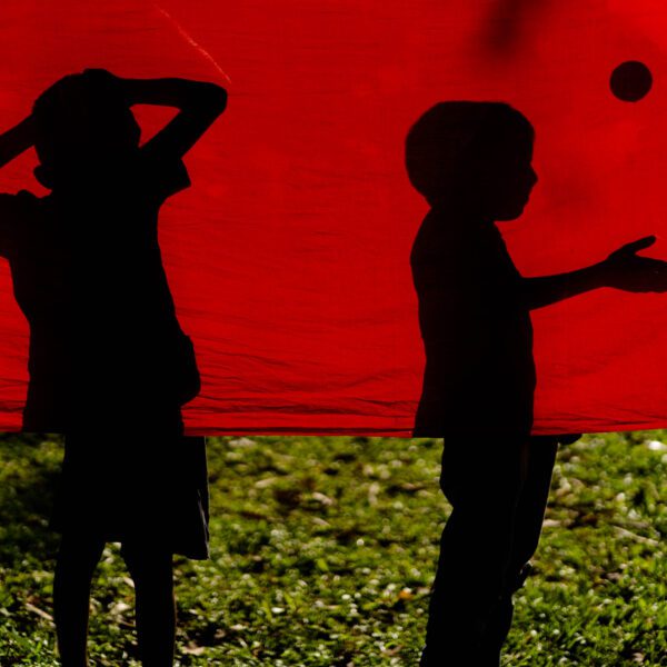 The silhouette of two boys playing behind a red cloth in Bangladesh